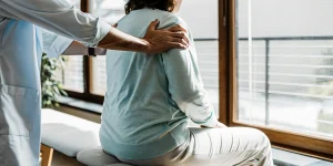 Chiropractor guiding a patient through a gentle stretch for sciatica nerve pain relief in a bright clinic