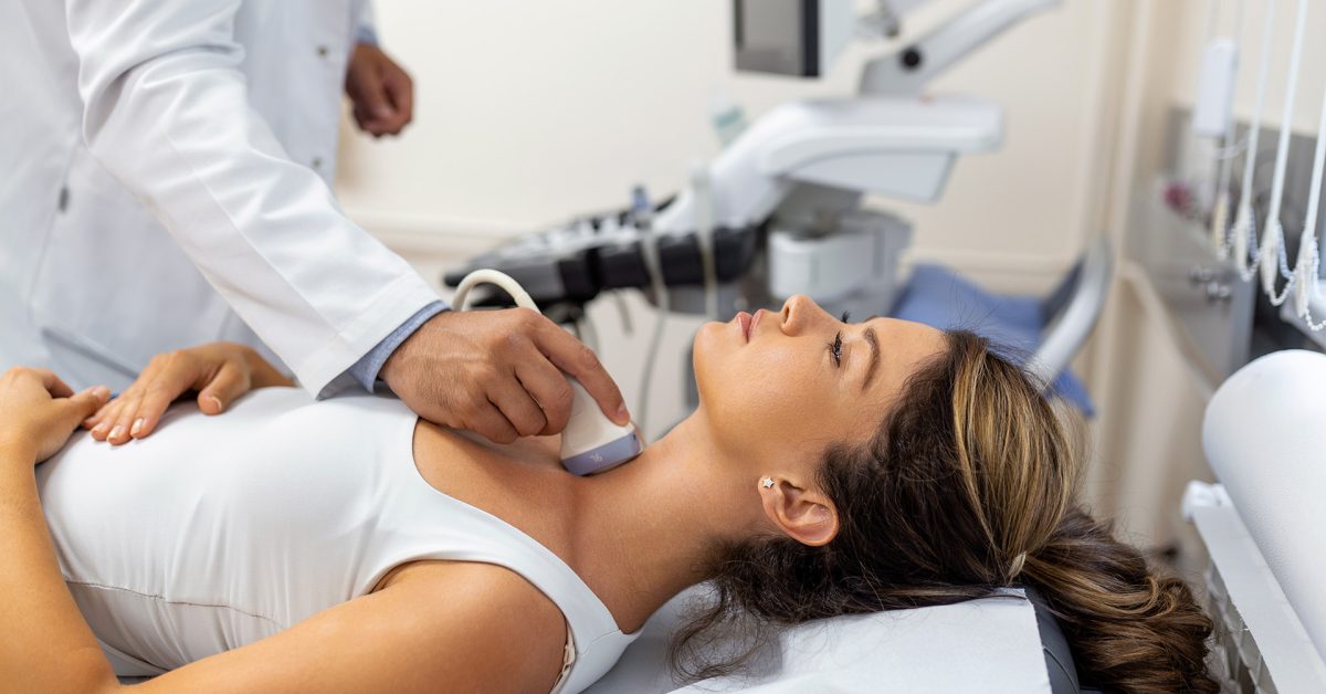Doctor making ultrasound of thyroid gland to woman patient in clinic. Diagnosis and treatment of autoimmune thyroiditis concept